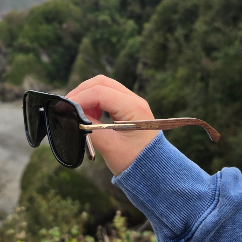 Tide & Palm sunglasses held up against the Devon coast, photographed by customer Lola